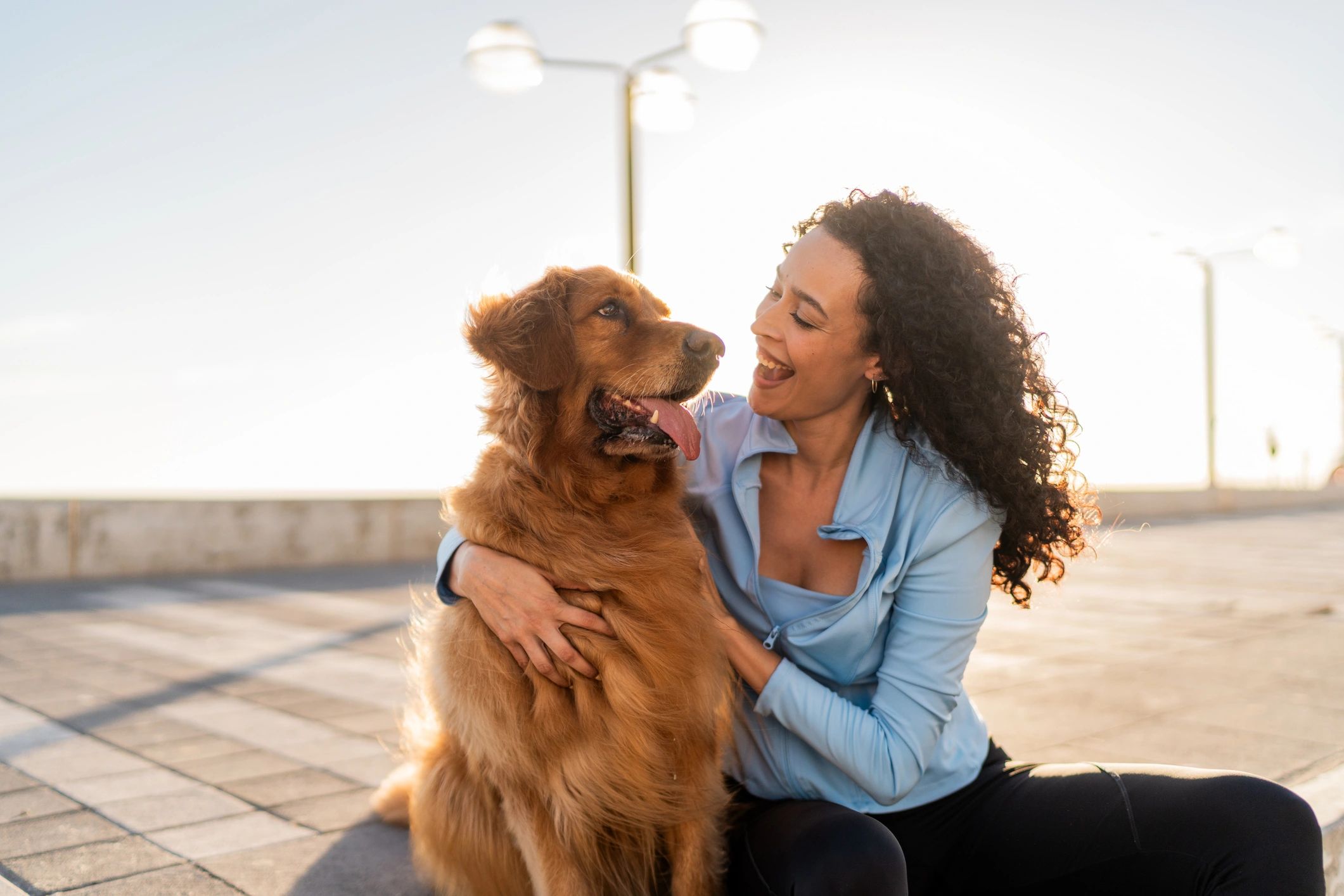 Pet owner embracing a golden retriever outdoors